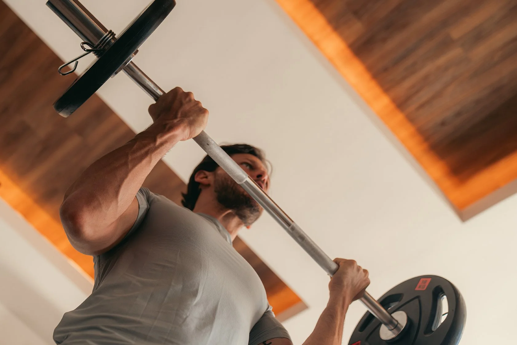 Hombre levantando una barra con discos de pesas en un gimnasio