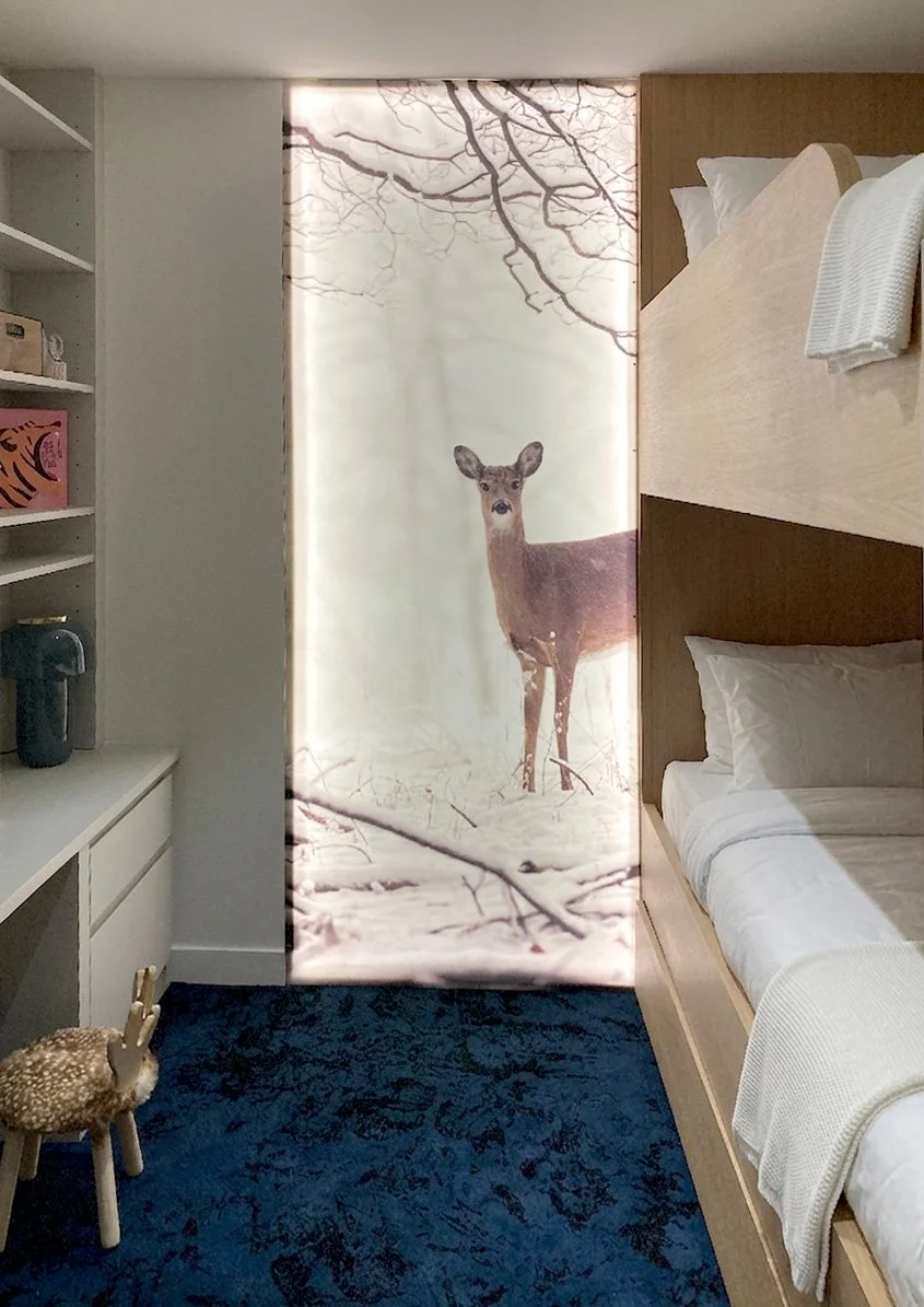 Rideau avec une image d'un cerf au centre, en arrière-plan des branches d'arbre dénudées, dans une chambre avec lits superposés et étagère avec des objets.