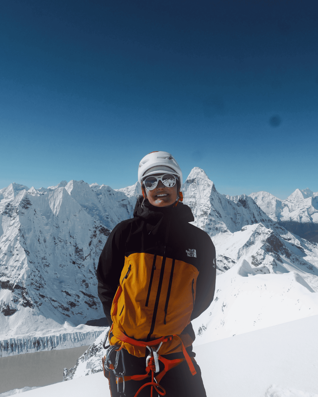 Personne équipée pour l'alpinisme dans un environnement de montagne enneigée avec de hautes montagnes et glacier en arrière-plan.