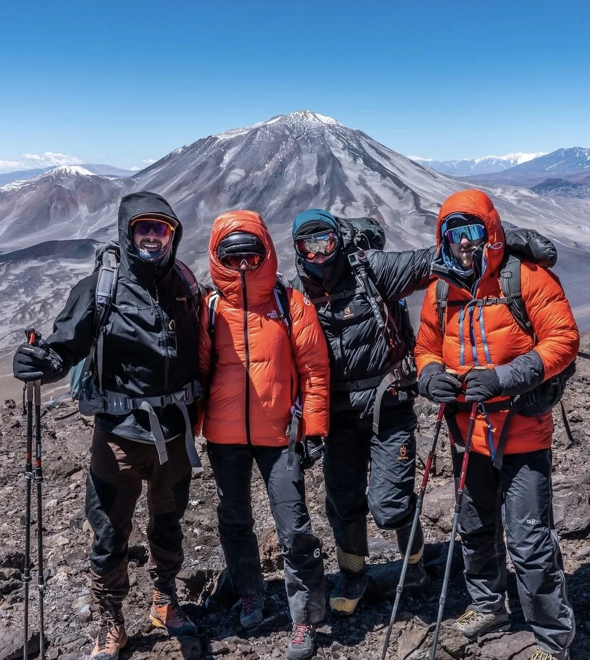 Groupe de quatre alpinistes en tenue de montagne, avec une montagne en toile de fond