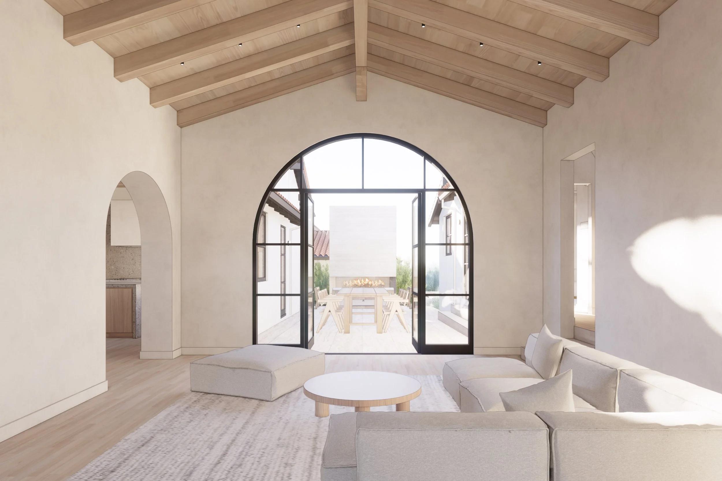 Living room with large arched glass doors opening to an outdoor patio dining area, light-colored sofa and ottoman, wooden ceiling beams, neutral walls, and natural light.