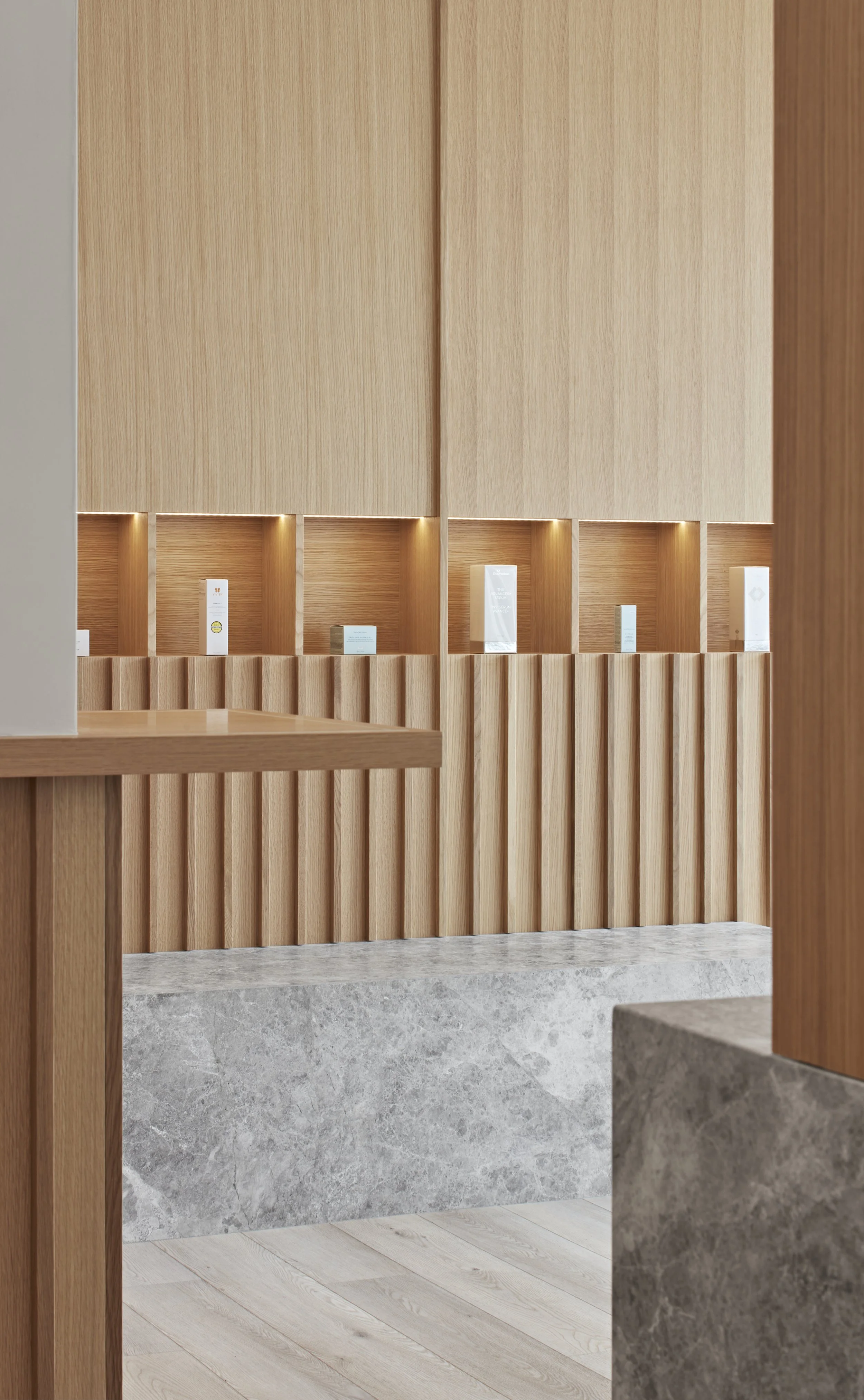 Interior view of a contemporary space with wooden paneling, illuminated display alcoves, and marble accents.