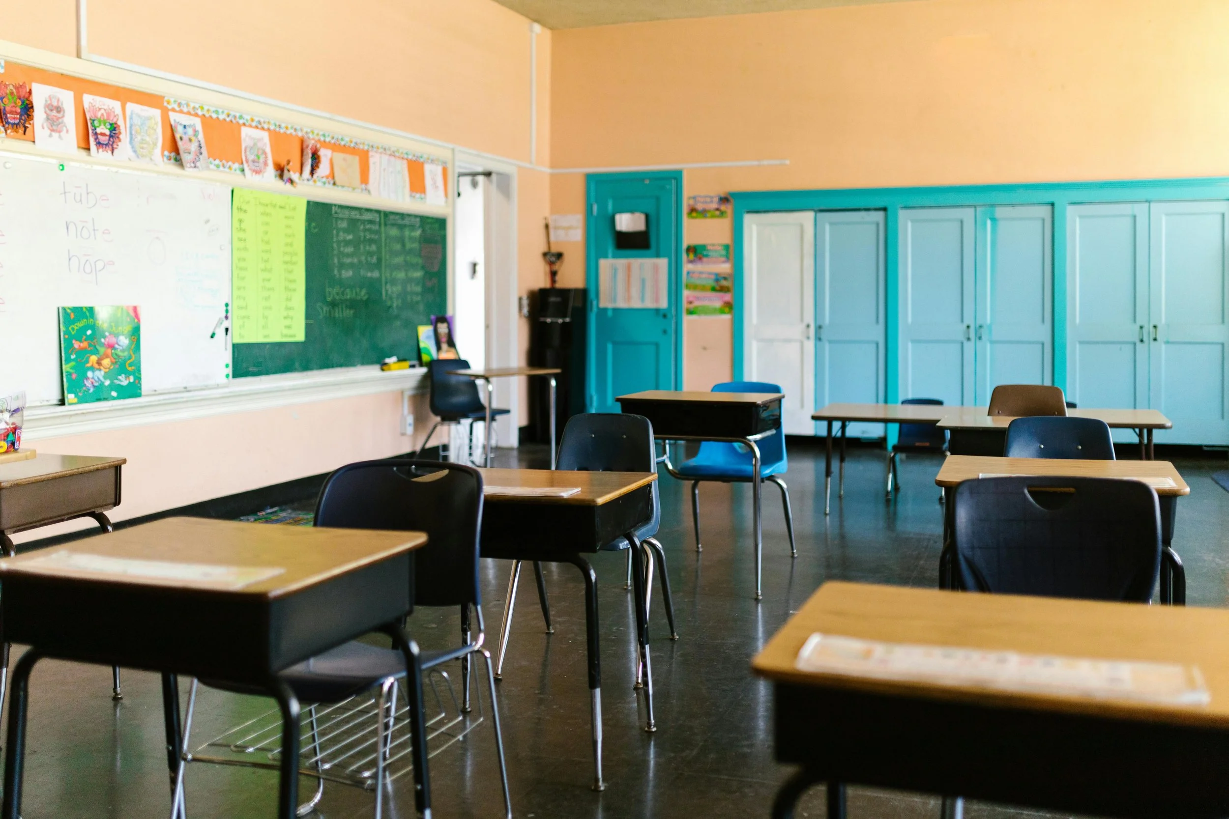 classroom with desks, chalkboard and cabinets