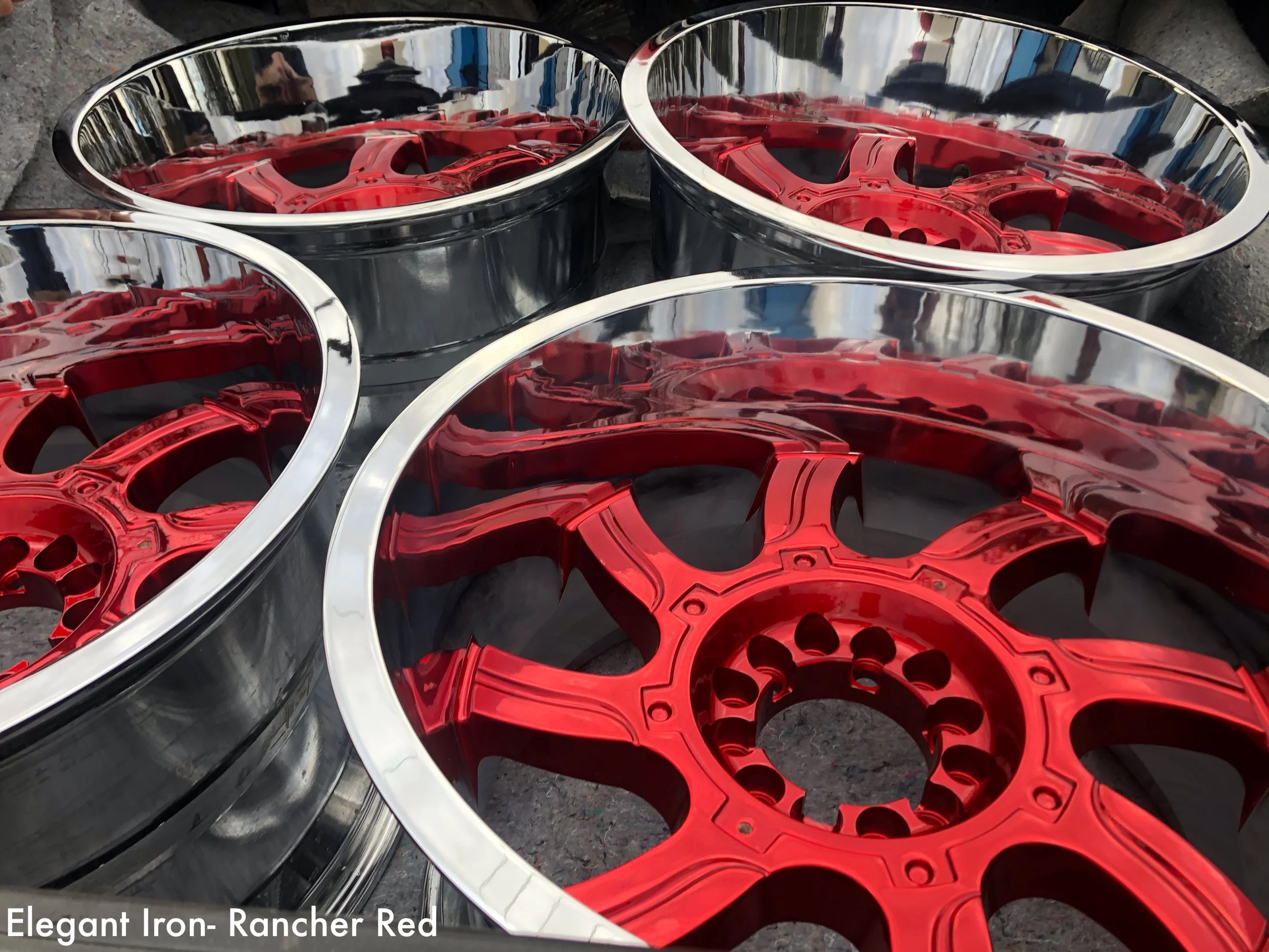 Four car wheels with red and chrome rims, three with red centers and silver outer edges, placed on a dark surface.