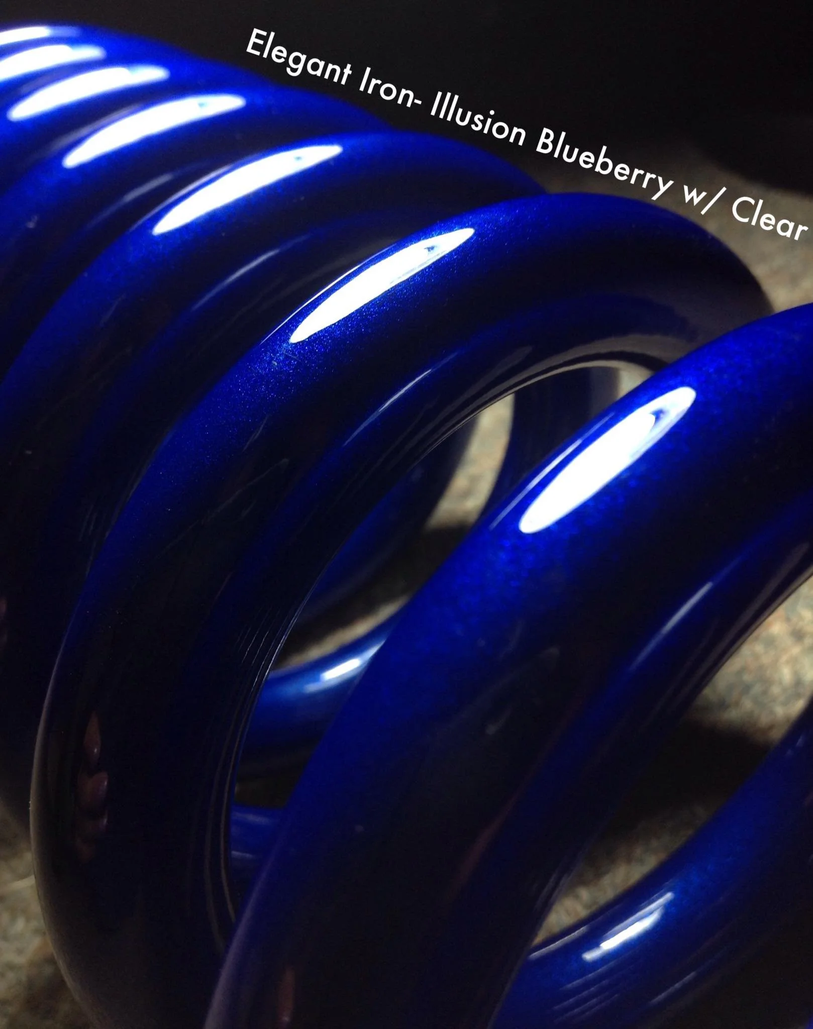 Close-up of a blue, glossy, curved object labeled 'Elegant Iron- Illusion Blueberry w/ Clear'.