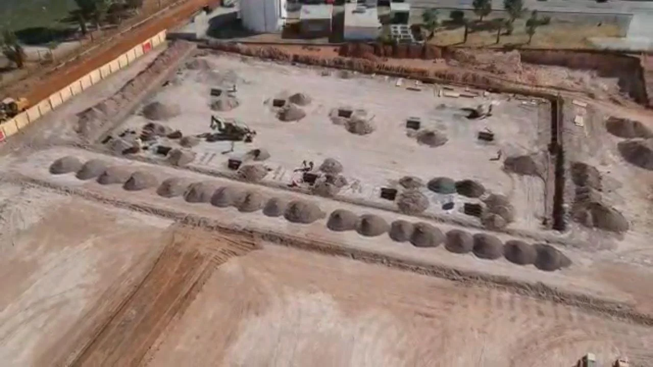 An aerial view of a construction site with large dome-shaped structures and excavated areas.