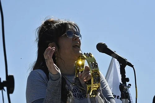 Woman leading a crowd in song with a tambourine