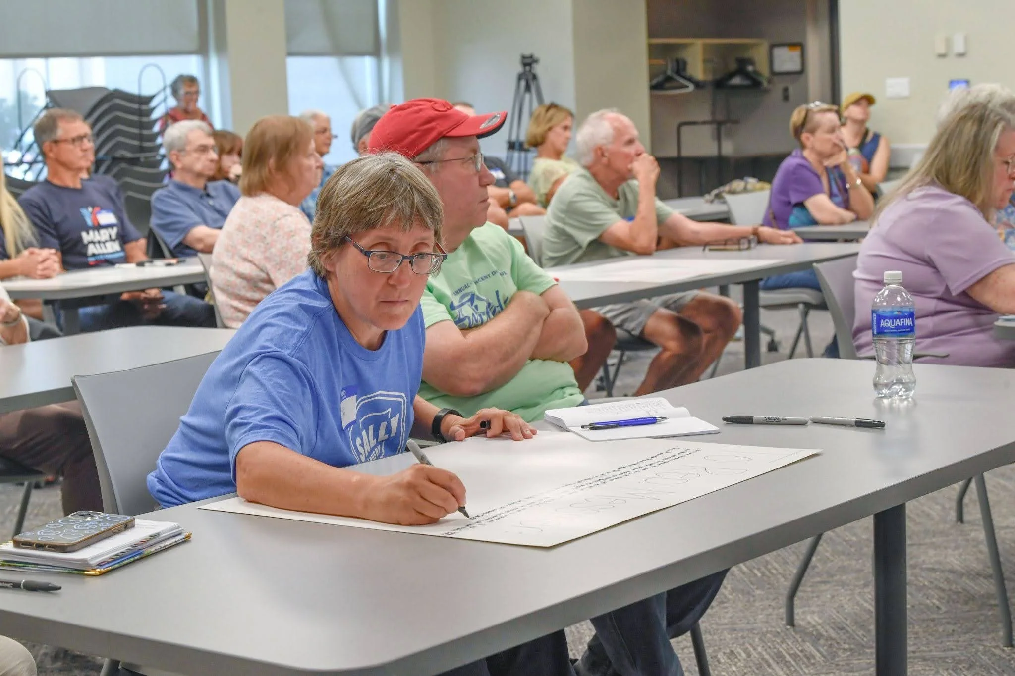 A town hall attendee writes a message to Mark Messmer on a posterboard