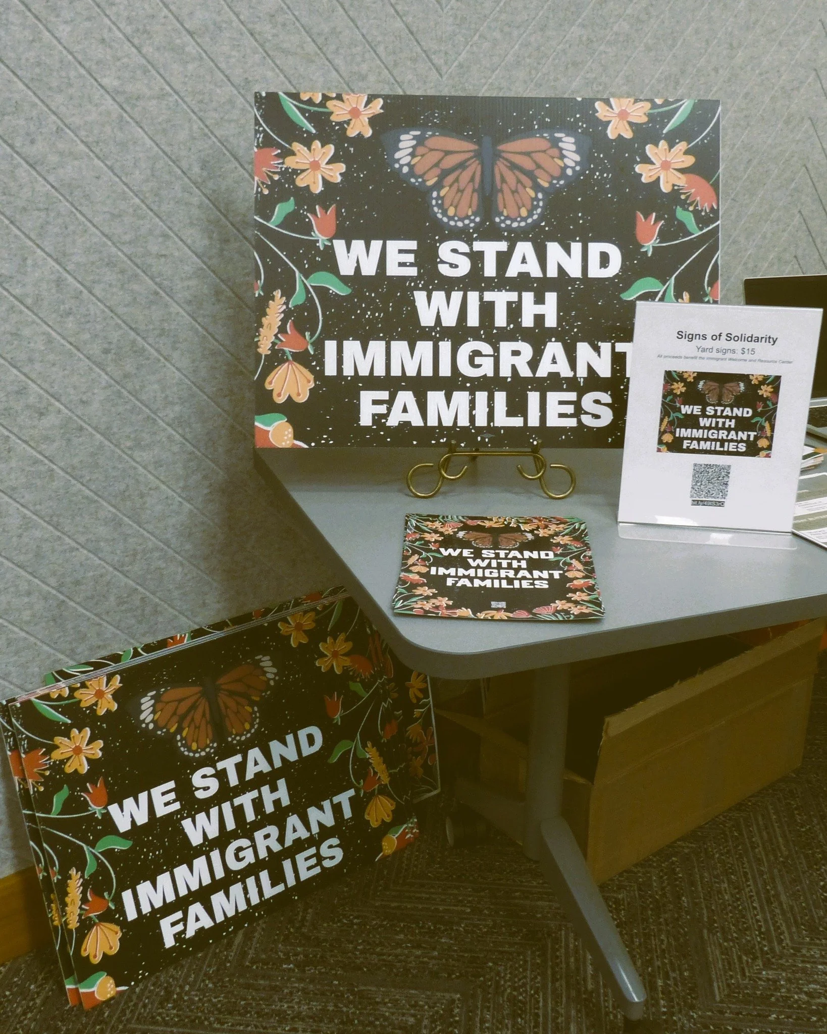 Yard signs saying "We Stand with Immigrant Famililes"
