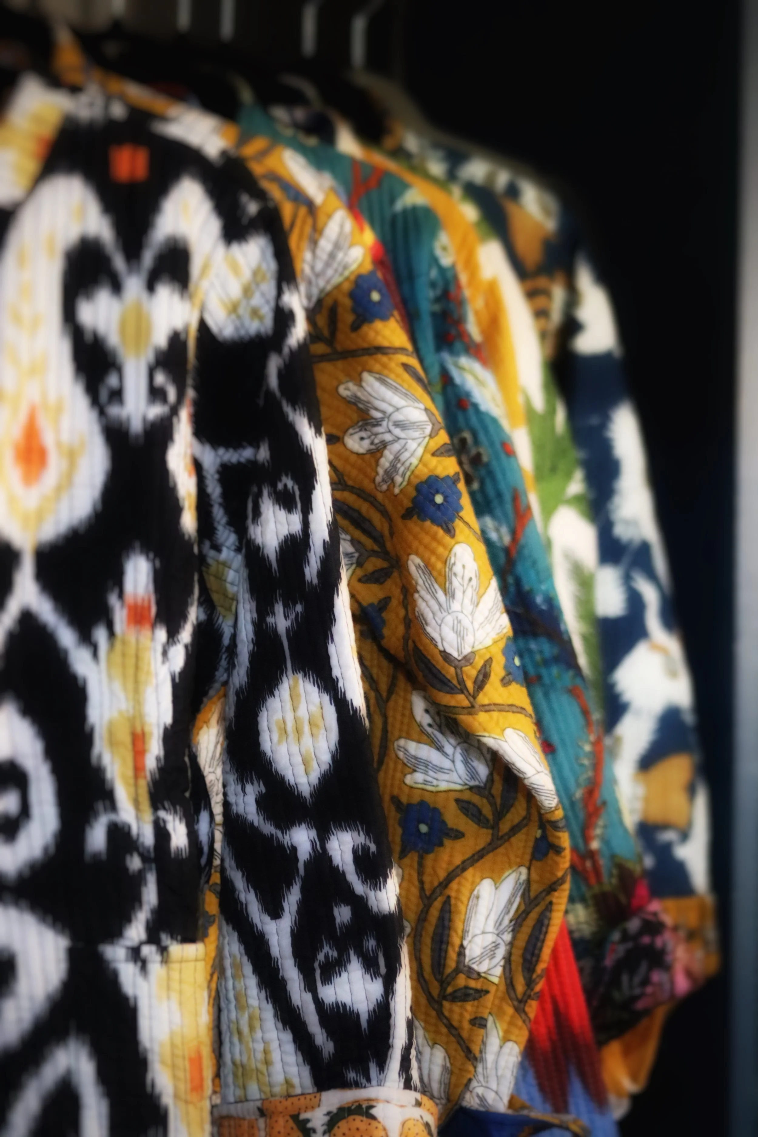 Close-up of colorful floral and animal print shirts hanging on a rack.