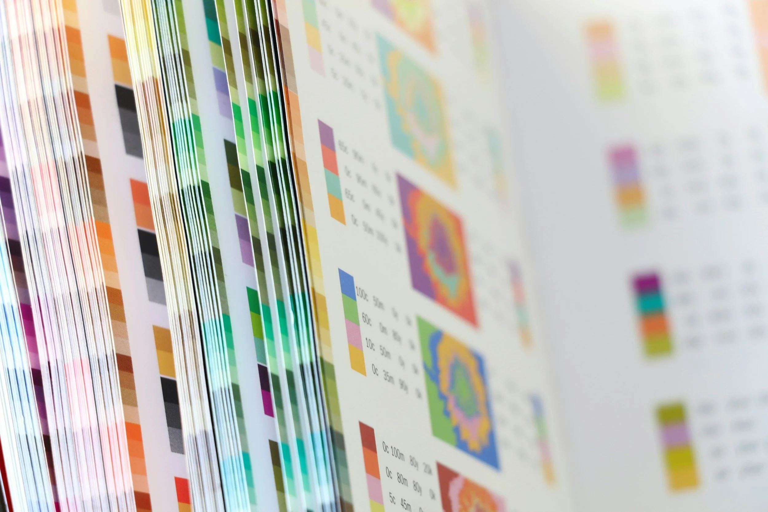 A printout of various color charts and graphs, some with visible color gradients and labels, with some sections blurred and distorted.