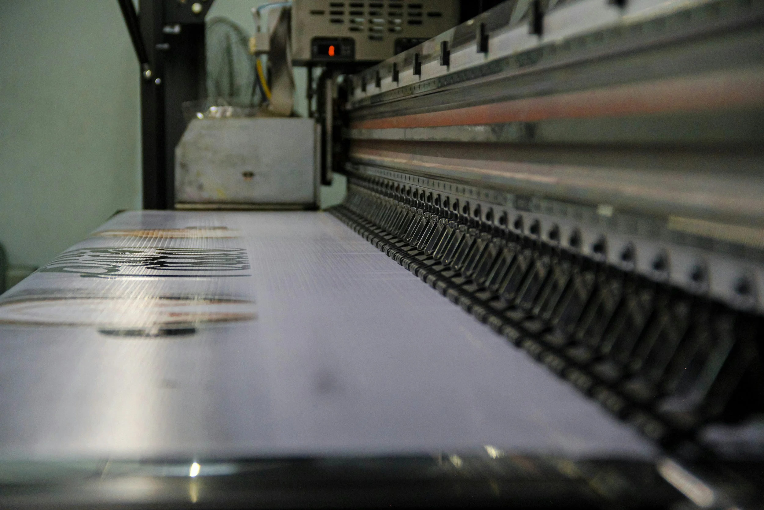 Close-up of a printing press in operation, printing labels or stickers with text on a sheet of material.