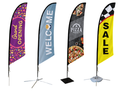 Four vertical fabric flags on metal stands with colorful designs and texts: "Grand Opening" in purple and yellow, "Welcome" in blue and white, a pizza image with the word "Pizza," and a yellow flag with the word "Sale."
