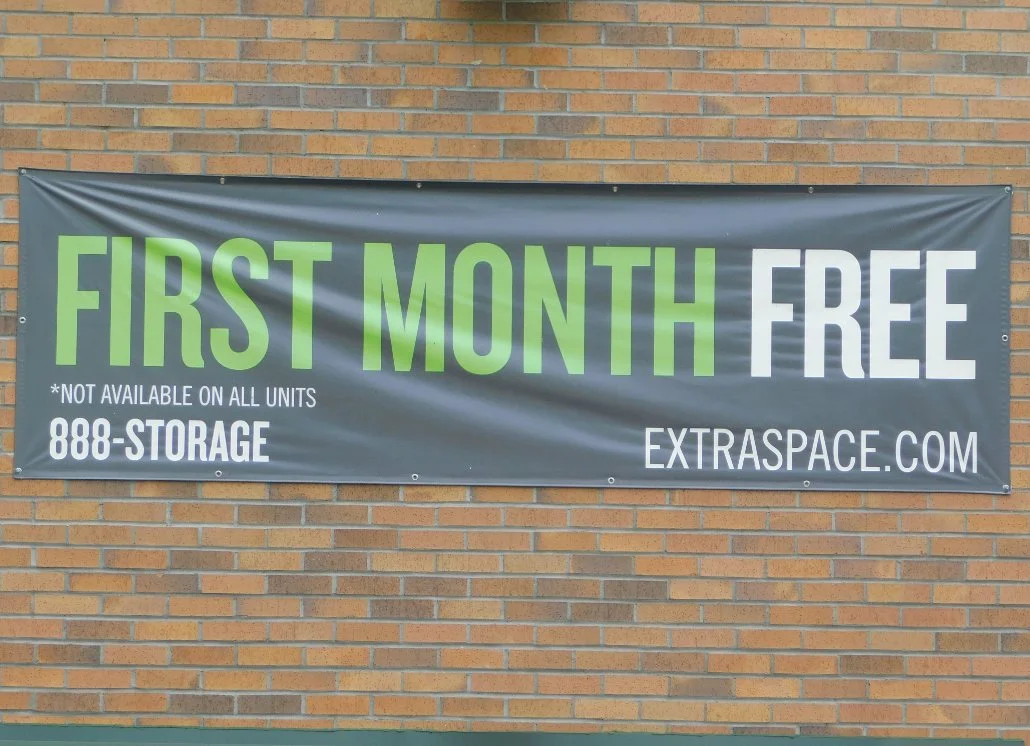 Banner advertising storage units with a first month free offer, not available on all units, with a website and phone number.