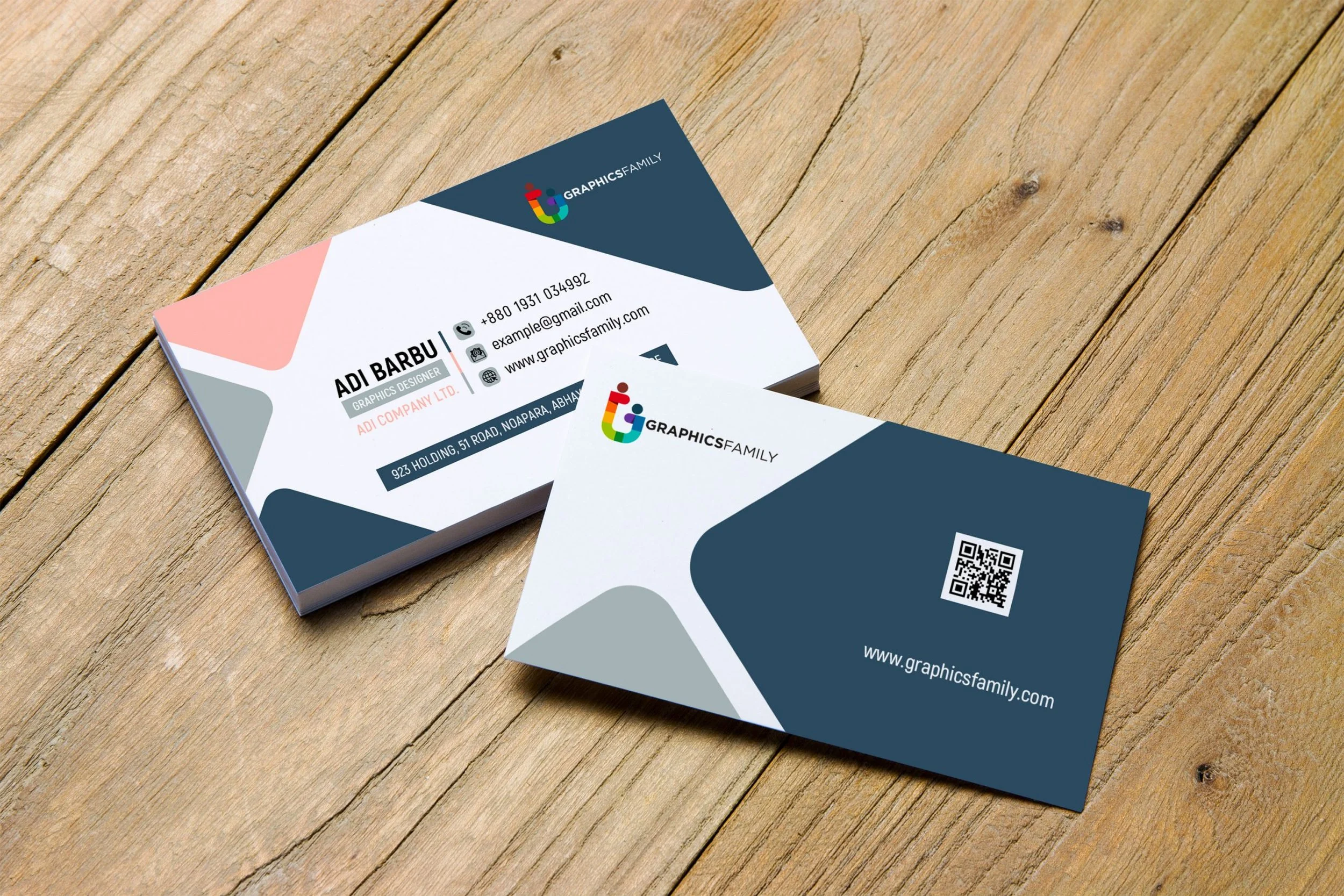 Business cards for Graphics Family on a wooden surface. One card shows contact details, the other features a QR code and website.