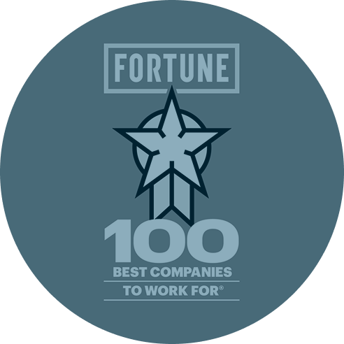 Blue circular badge with a star design, featuring the words "Fortune 100 Best Companies to Work For," conveying prestige and achievement.