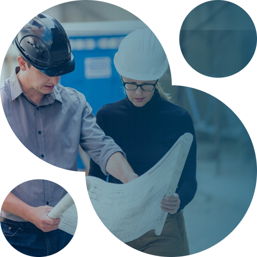 Two construction workers in hard hats reviewing blueprints together on a job site