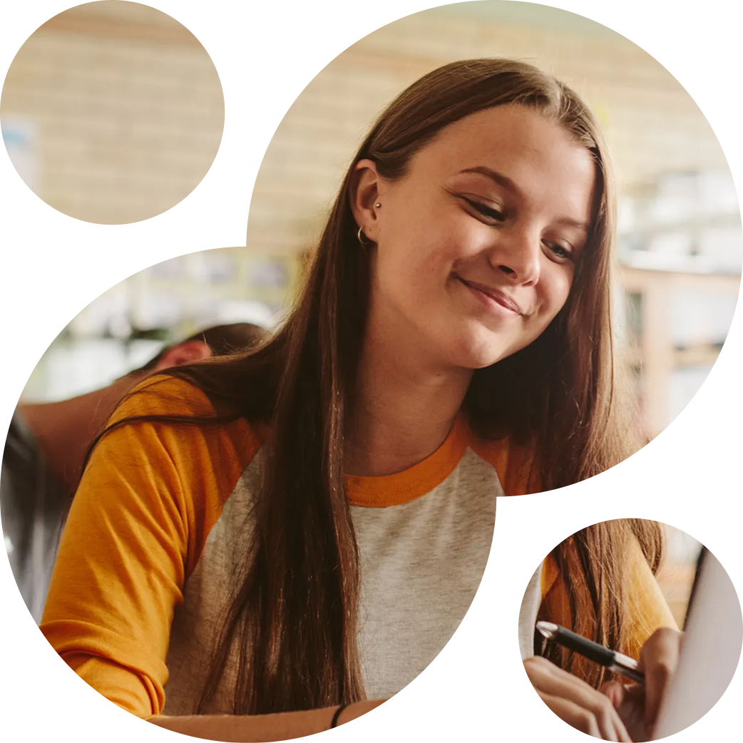 A young woman with long brown hair and a bright smile looking at her phone in a cozy cafe.