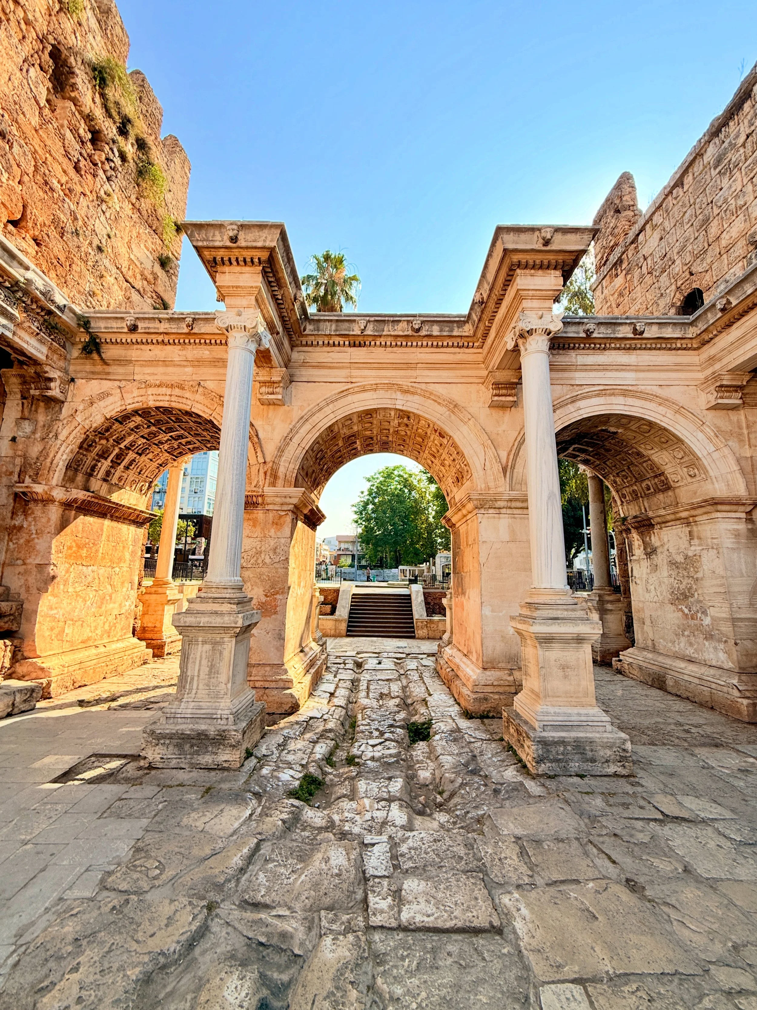 Ancient stone ruins with columns and arches, cobblestone pathway, and clear blue sky.