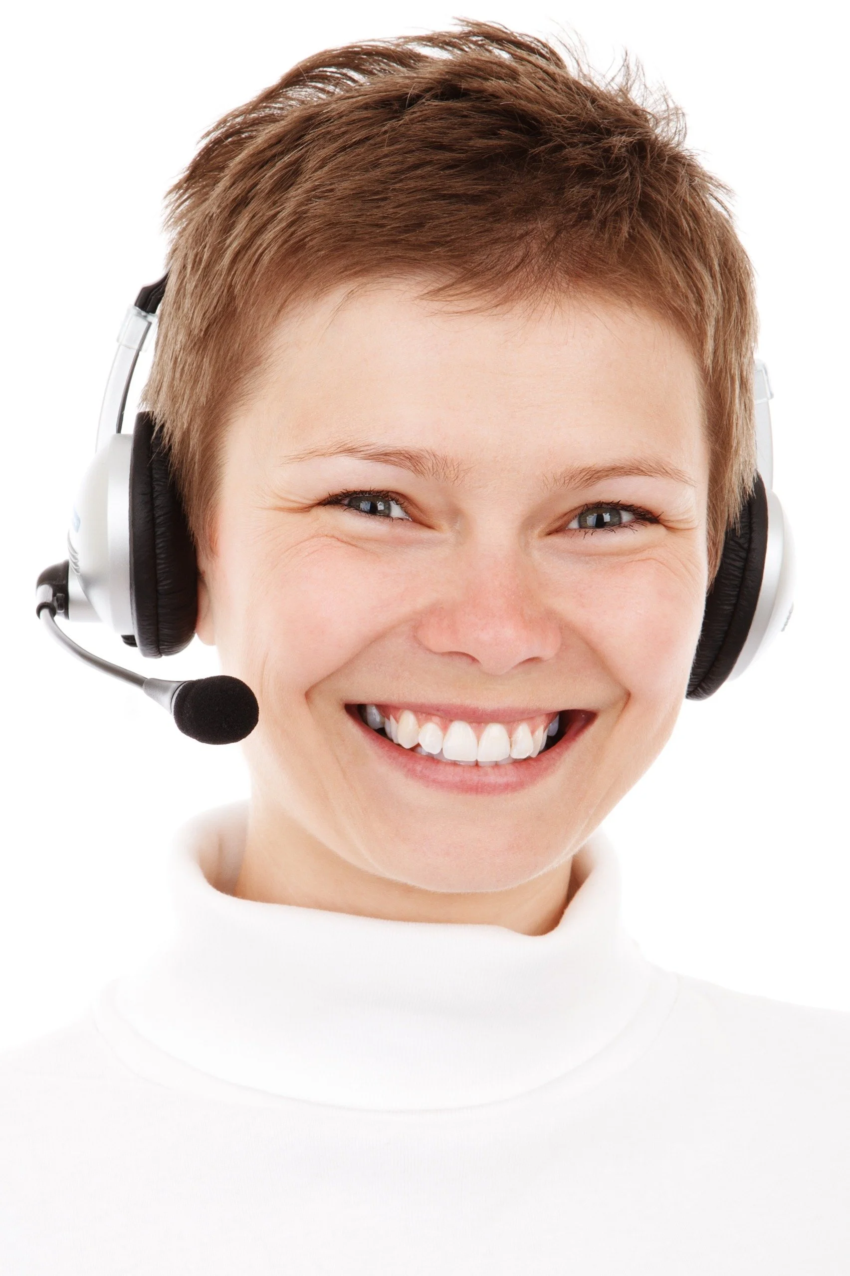 A smiling woman with short brown hair wearing a white turtleneck and a black and white headset with a microphone.