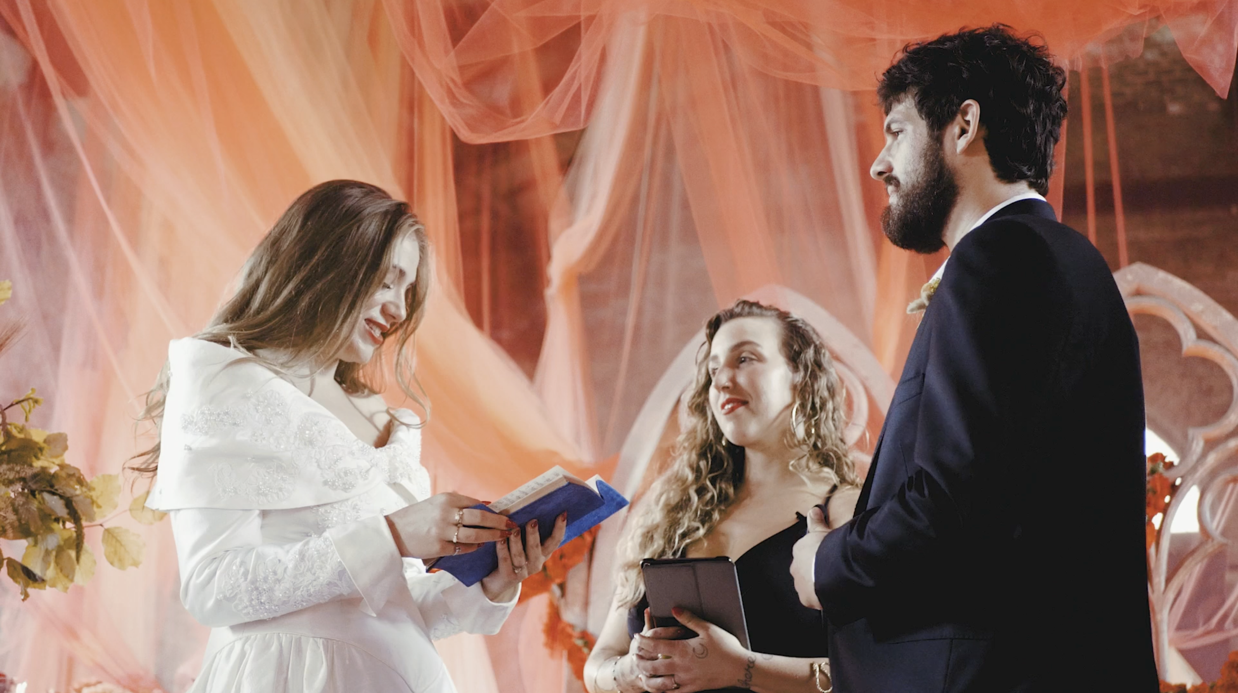 A bride and groom exchanging vows under a decorated backdrop at a wedding ceremony.