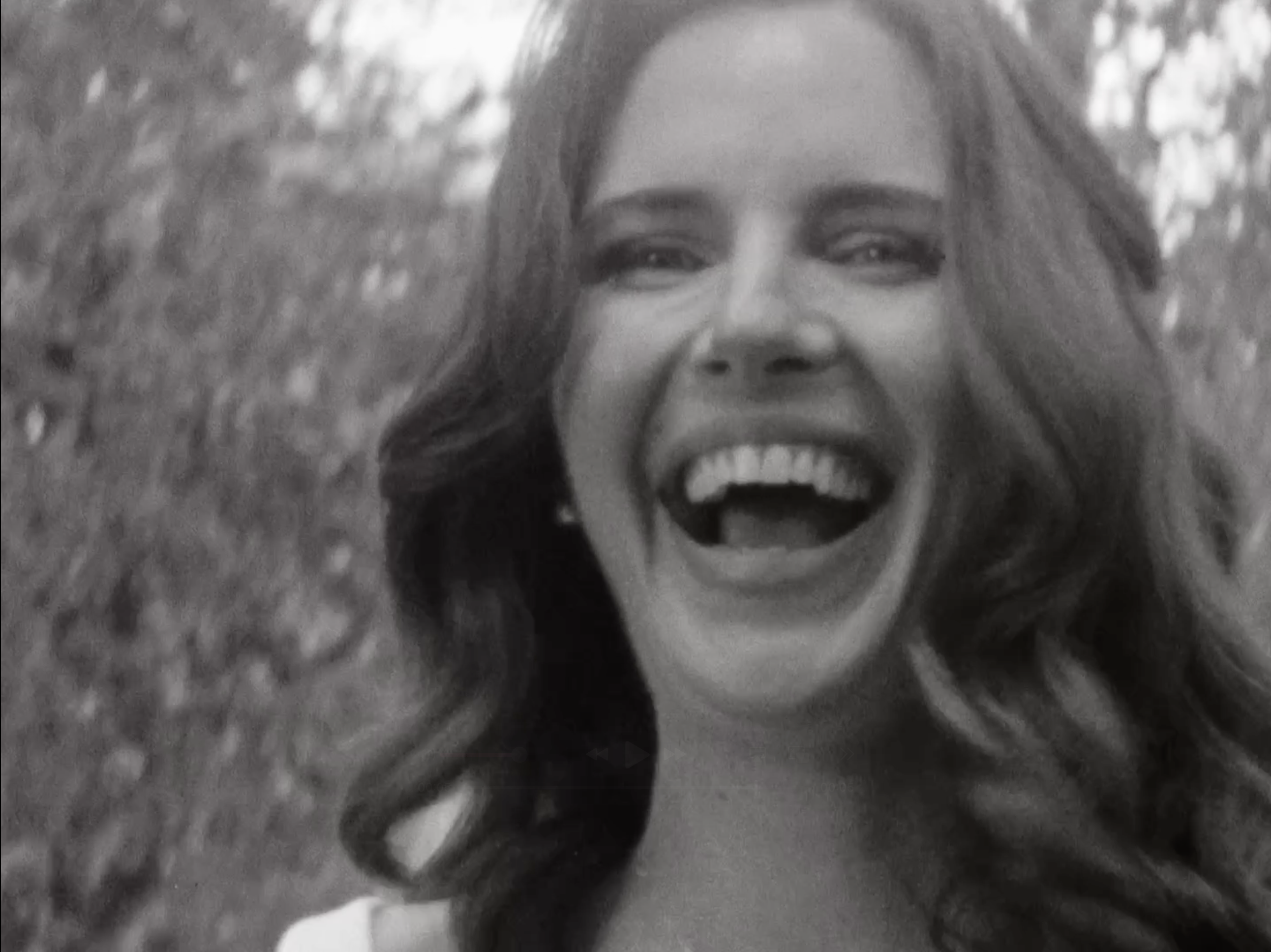 Black and white photo of a woman with curly hair singing with her mouth open.