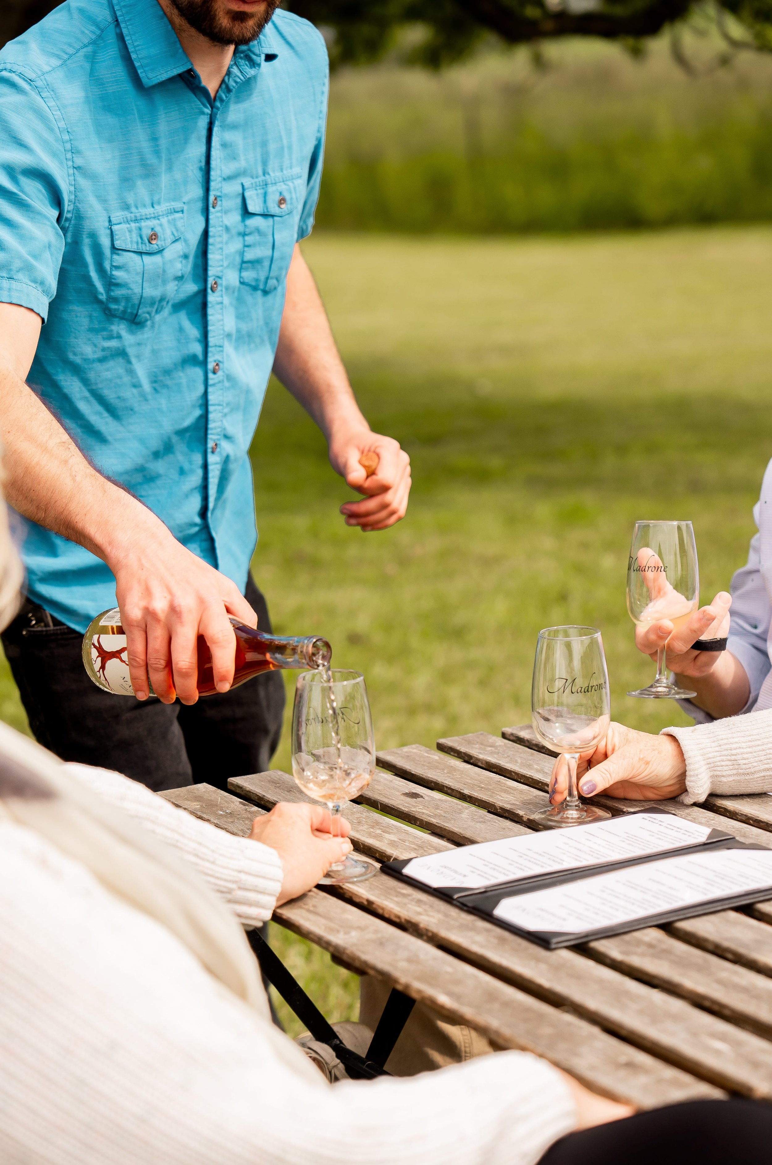 Man pouring wine into wine glass outdoors