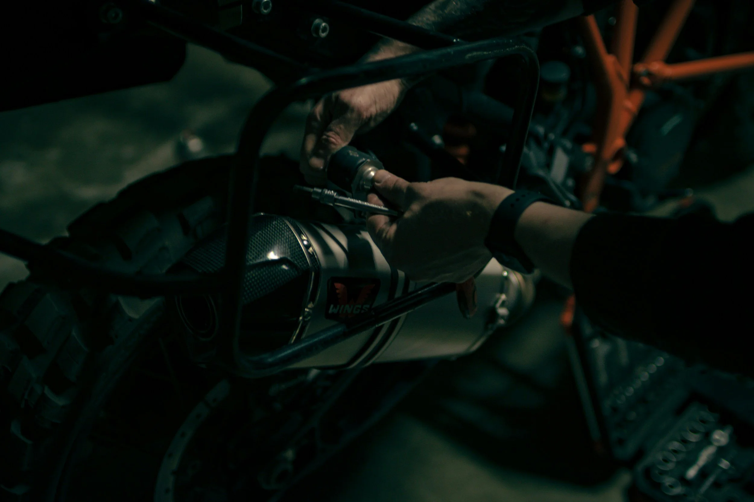 Person working on a motorcycle engine in a dimly lit garage