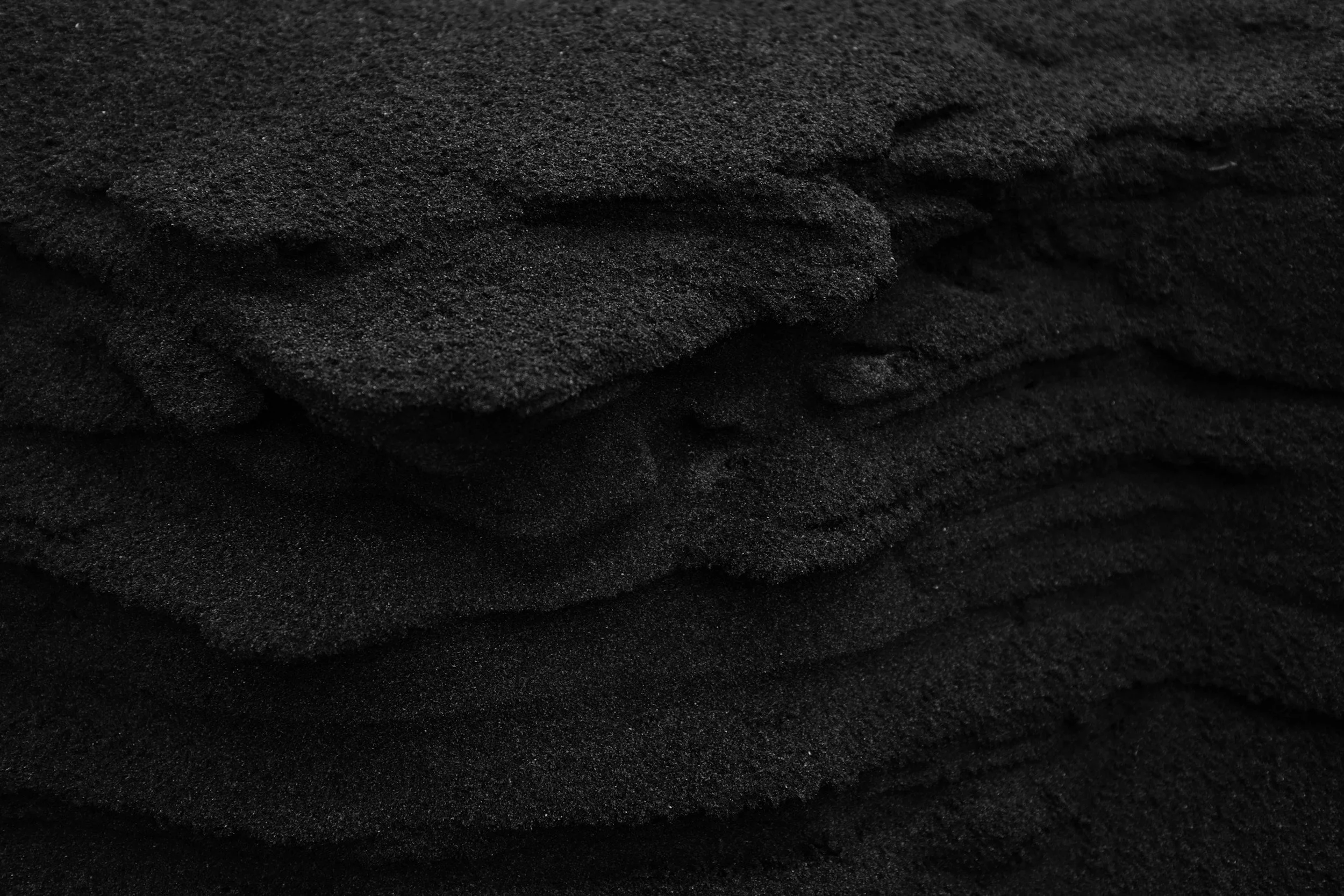 Close-up photo of stacked black sandpaper sheets.