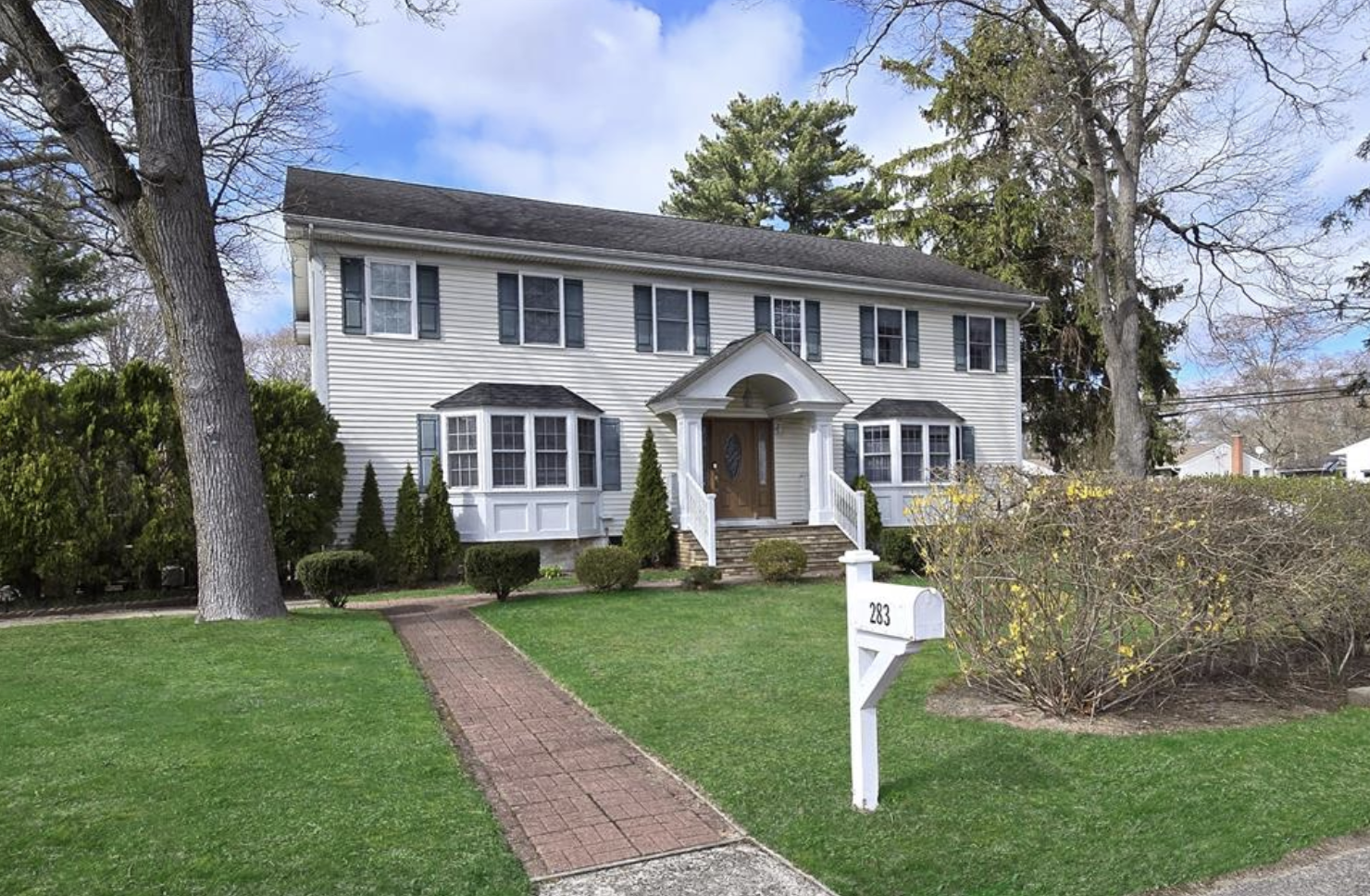 View from street of large white home with black shutters at 283 Elizabeth Ave, Holbrook, NY