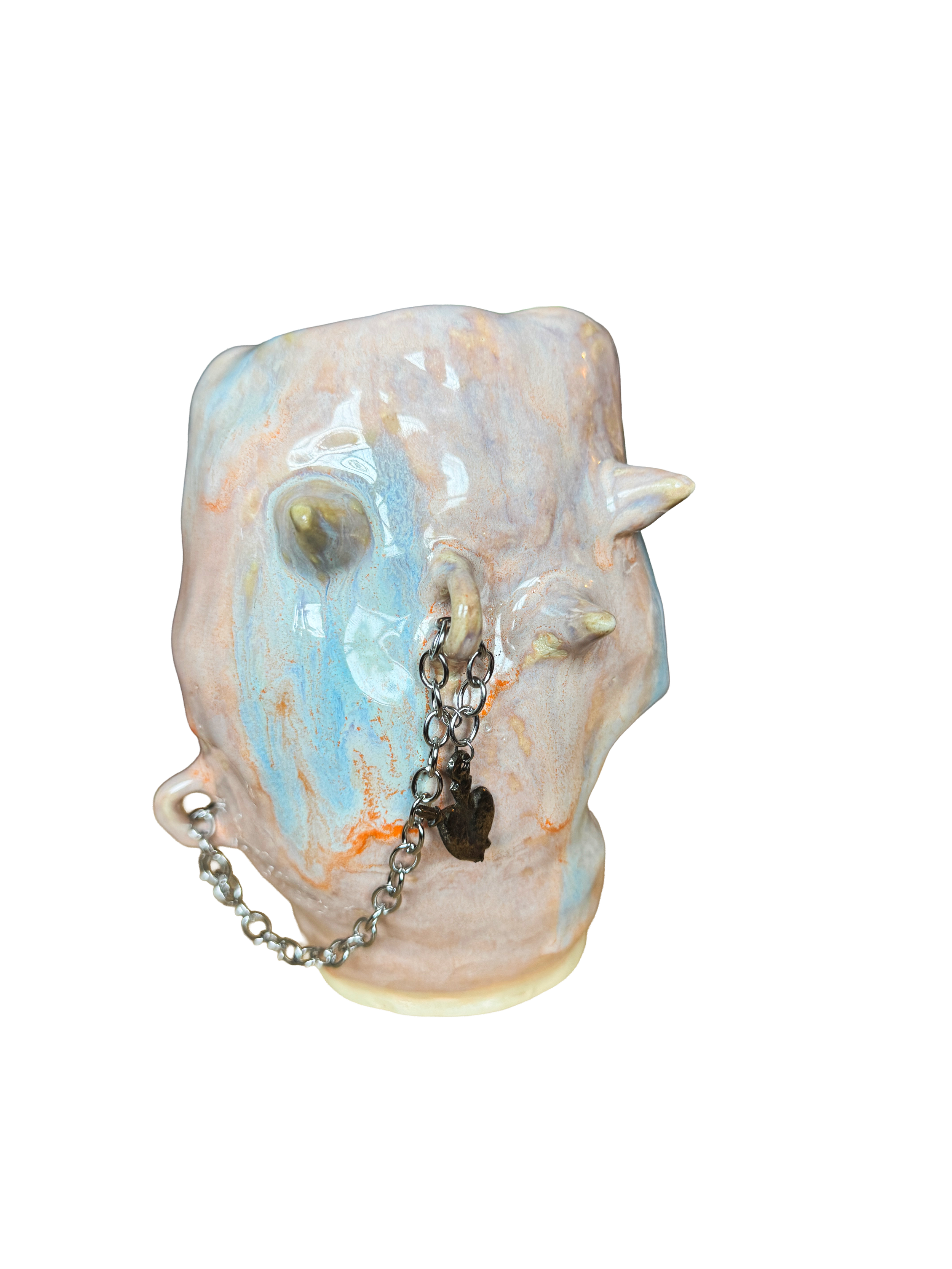 A ceramic piece shaped like a human face with multi-colored glaze, featuring piercings and a chain necklace.