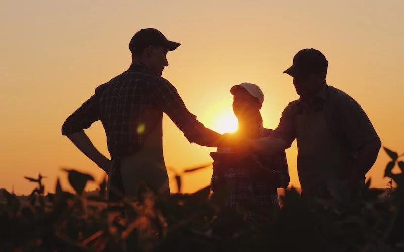 Farmers shaking hands with sun in background