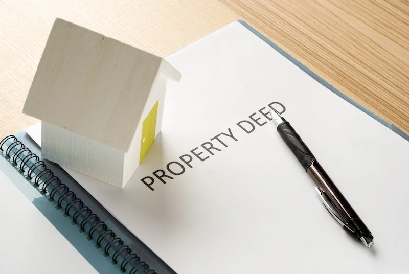 Notebook that says "Property Deed" with pen and model home