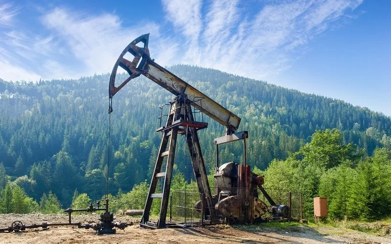 Oil rig in front of trees and blue sky