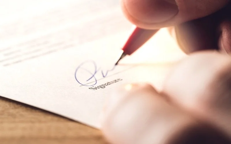 Hand signing a document with pen