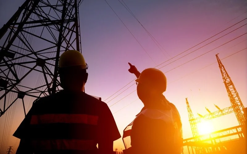 Men pointing at an electric tower