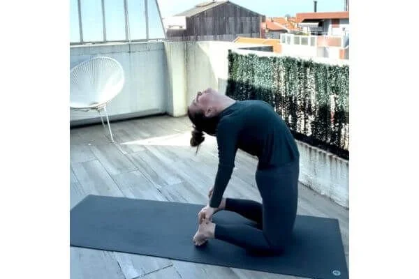 trish corley in camel pose on a yoga mat