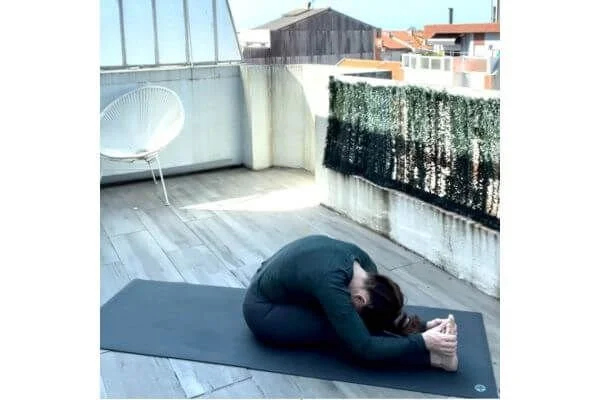 trish corley in seated forward fold on a yoga mat
