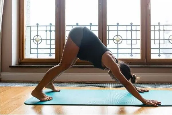 yoga student in downward facing dog with bent knees to restore neutral spine