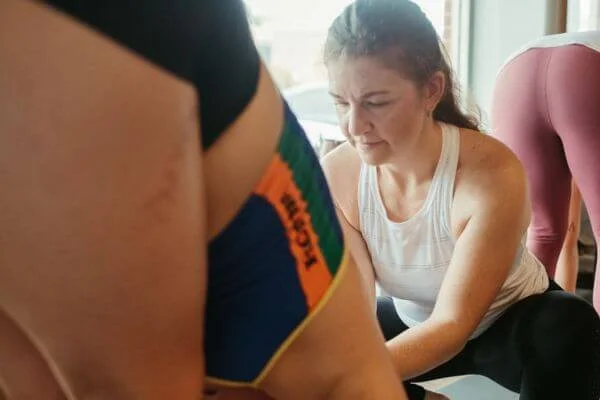 Trish assisting a student for Managing Yoga Students with Injuries & Pain