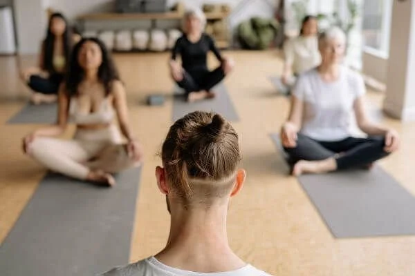 yoga teacher in front of class asking about injuries
