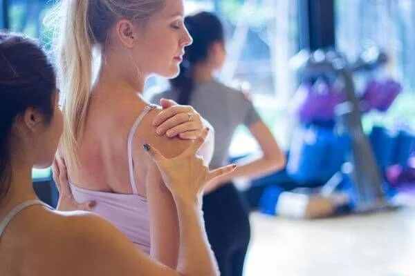 yoga teacher assisting a student with a shoulde injury
