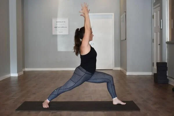 trish corley in a warrior 2 in yoga studio energy