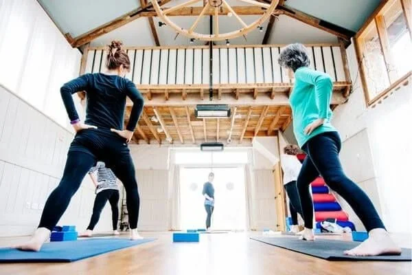 yoga class in a studio with students aligning their hips in warrior one