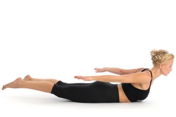 yoga student in locust posture looking forward with elongation of cervical spine