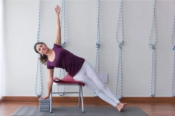 yoga student demonstrating side plank with chair in Iyengar style