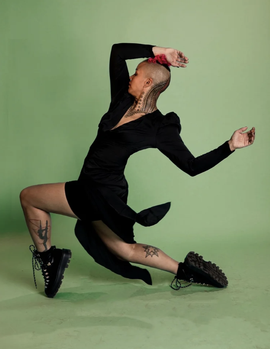 Executive director, Helen Estrella, posing dynamically against a green background.