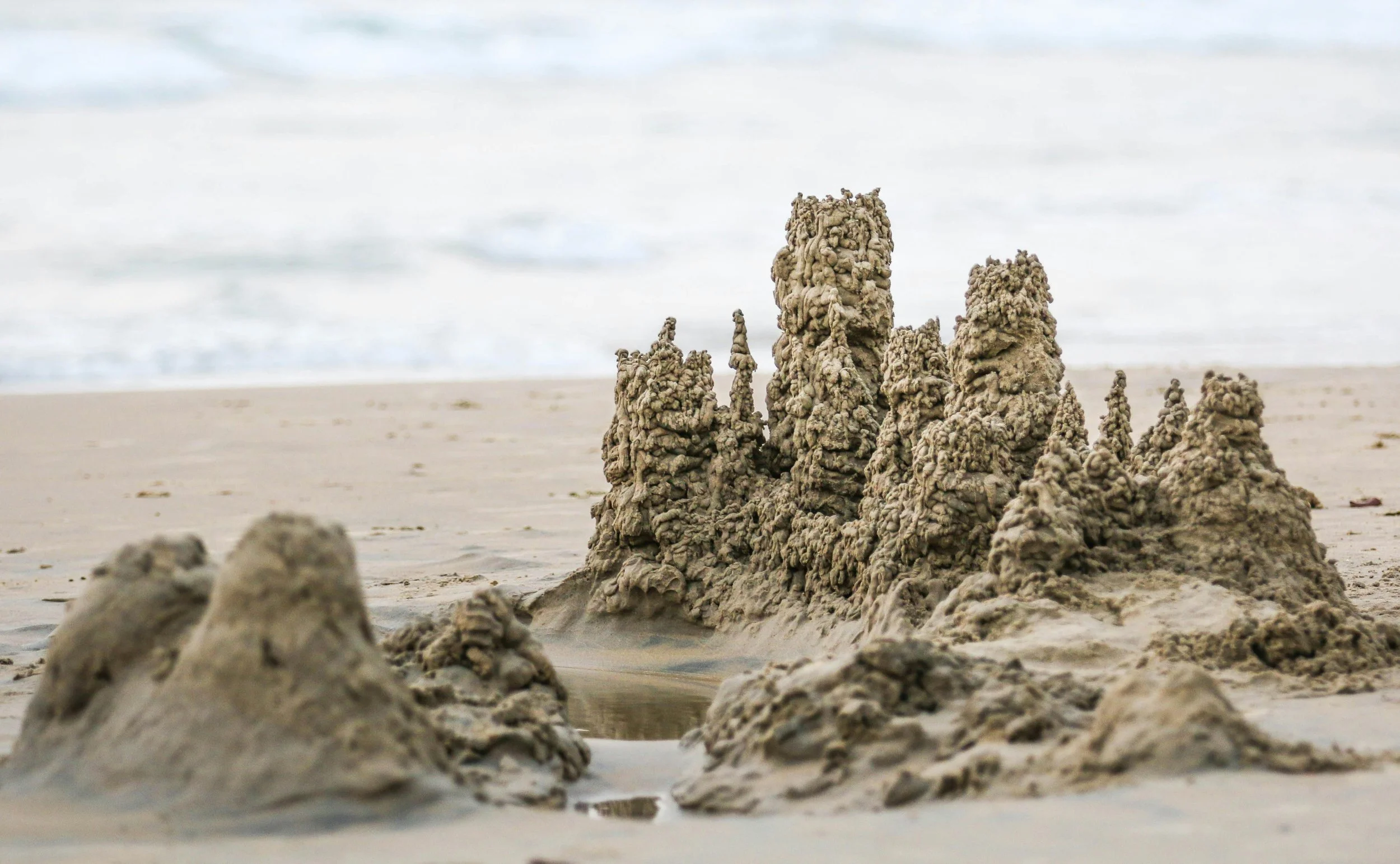 Sandcastle formation on a beach with the ocean in the background.