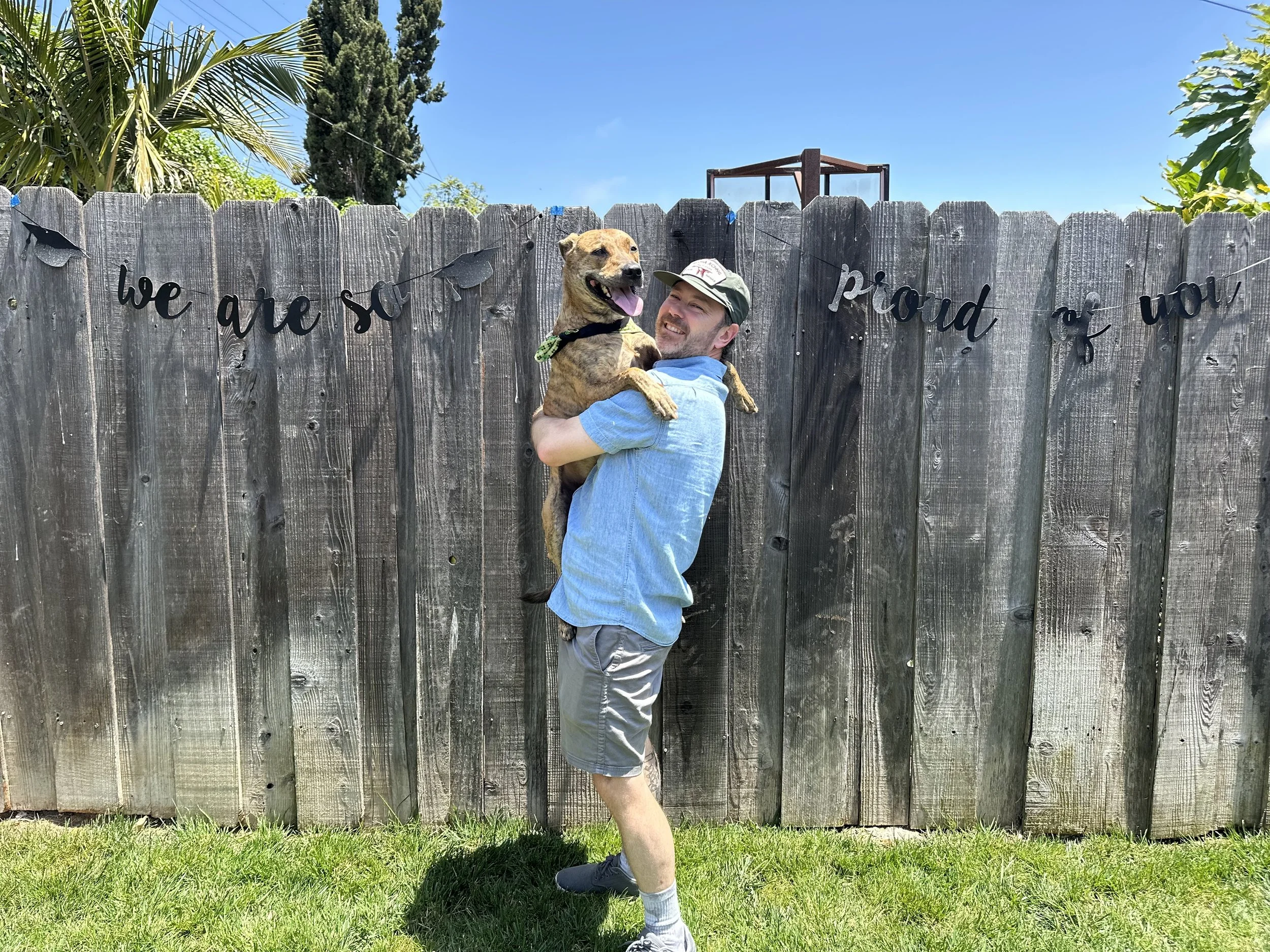 Business owner holding brindle colored dog with smiling faces