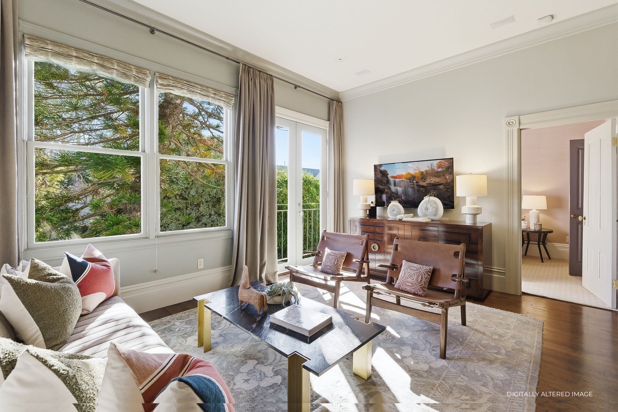 Living room with large windows, beige curtains, wooden furniture, flat-screen TV, decorative lamps, and a sofa with colorful pillows